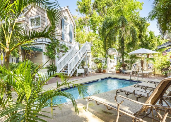 Lush outdoor area with a swimming pool next to a hotel